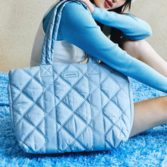 Woman with Amazing Song light blue quilted tote bag on blue textured rug