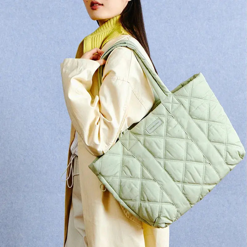 Woman wearing yellow scarf and cream coat carrying large quilted tote bag, Amazing Song