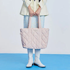 Woman holding a large quilted pastel pink tote bag, white boots, blue skirt, Amazing Song