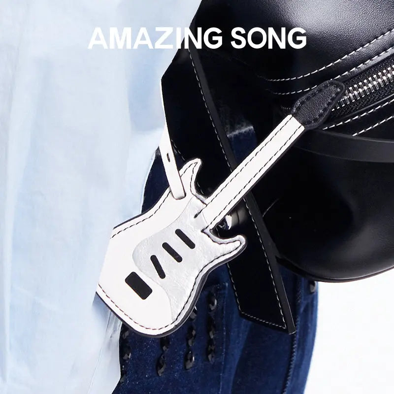 Amazing Song guitar-shaped bag tag on black handbag, stylish accessory close-up