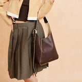 Woman with brown leather shoulder bag, pleated skirt, and cropped jacket, Amazing Song