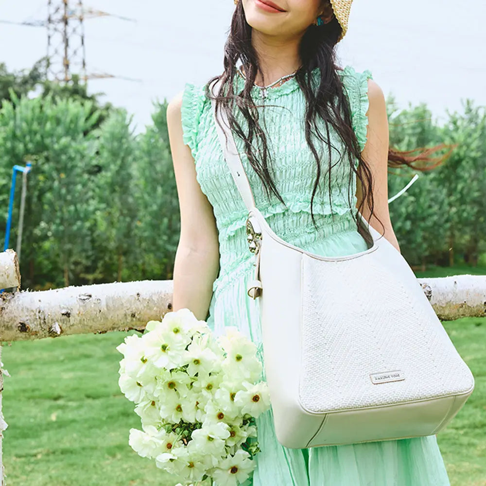 Woman in green dress with white handbag holding flowers outdoors, Amazing Song style
