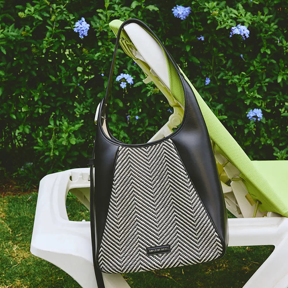 Amazing Song herringbone handbag on outdoor lounge chair with garden flowers