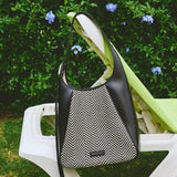 Amazing Song herringbone handbag on outdoor lounge chair with garden flowers