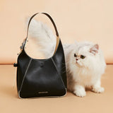Amazing Song black leather handbag with a fluffy white cat on beige background