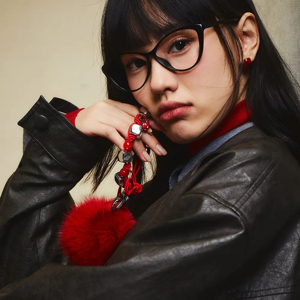Woman in black glasses and leather jacket holding red fluffy keychain, Amazing Song style