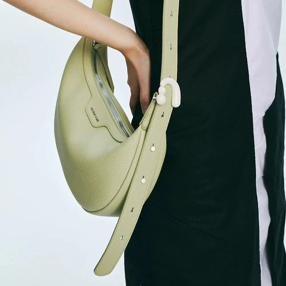 Close-up of green leather Amazing Song shoulder bag with adjustable strap on model