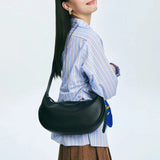 Woman wearing blue striped shirt and brown skirt with black Amazing Song shoulder bag