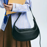 Person holding folders and wearing a black Amazing Song shoulder bag, striped shirt, brown skirt