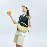 Smiling woman in a casual outfit with a light yellow sling bag holding an orange, Amazing Song official website