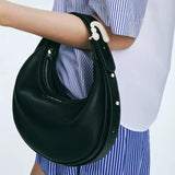 Black leather shoulder bag with white accents, worn with a blue striped shirt, Amazing Song