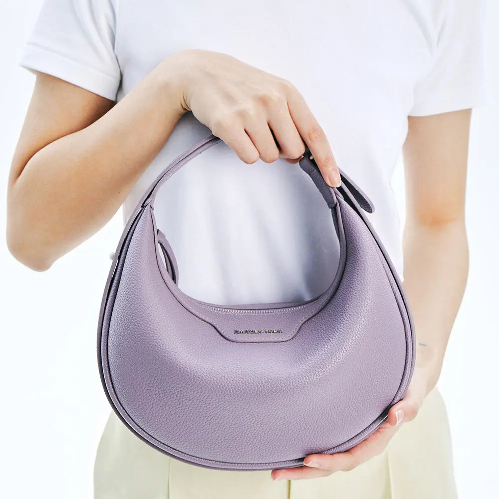 Woman holding a lilac Amazing Song handbag against a white background