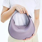 Woman holding a lilac Amazing Song handbag against a white background