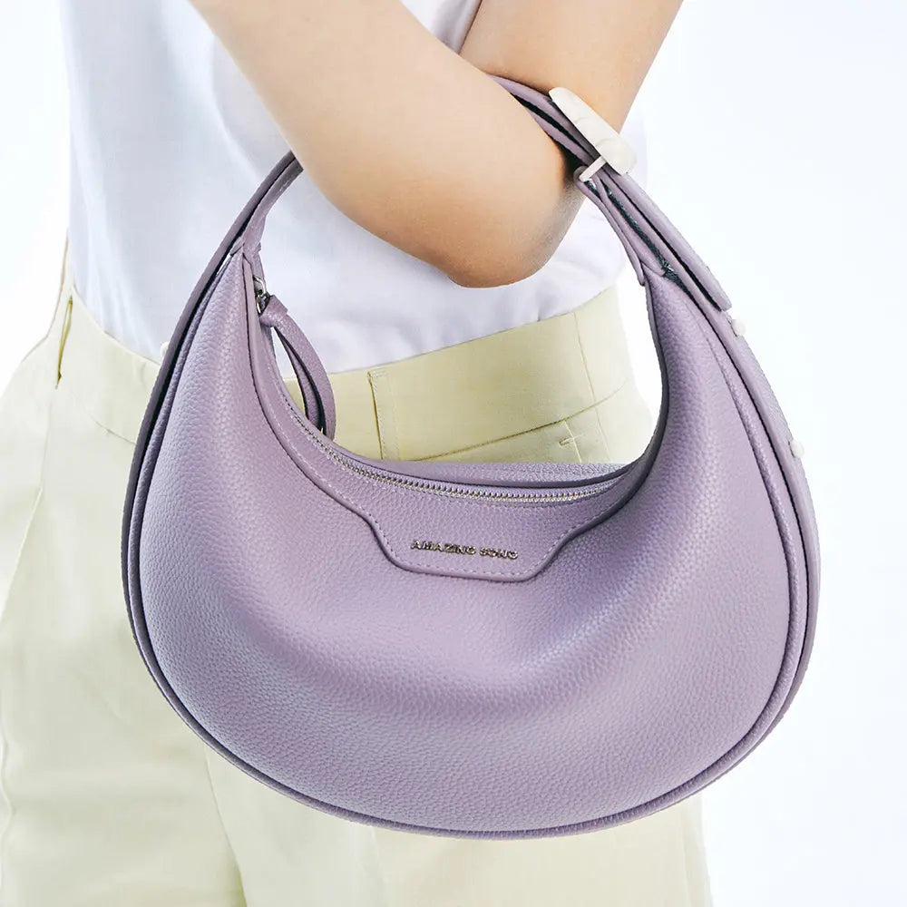 Woman carrying lilac Amazing Song handbag on her arm, white top and light beige pants