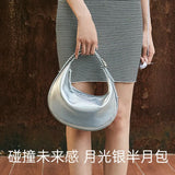 Woman holding silver crescent shoulder bag, striped dress, Amazing Song accessory