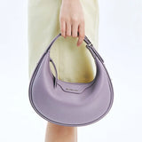 Woman holding a lilac Amazing Song crescent handbag against a light background