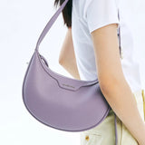 Woman carrying a lavender Amazing Song shoulder bag, white shirt, yellow pants