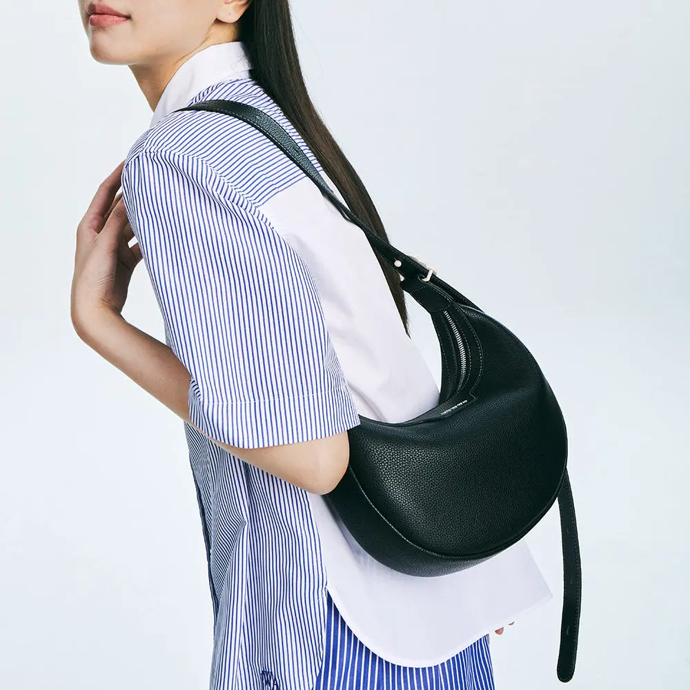 Woman in striped shirt carrying black leather shoulder bag, Amazing Song fashion