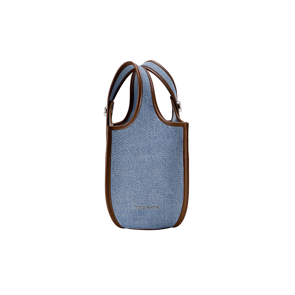 Amazing Song blue denim tote bag with brown leather trim on white background