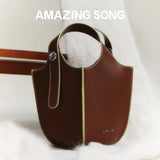 Amazing Song brown leather handbag with yellow trim on soft white fabric background