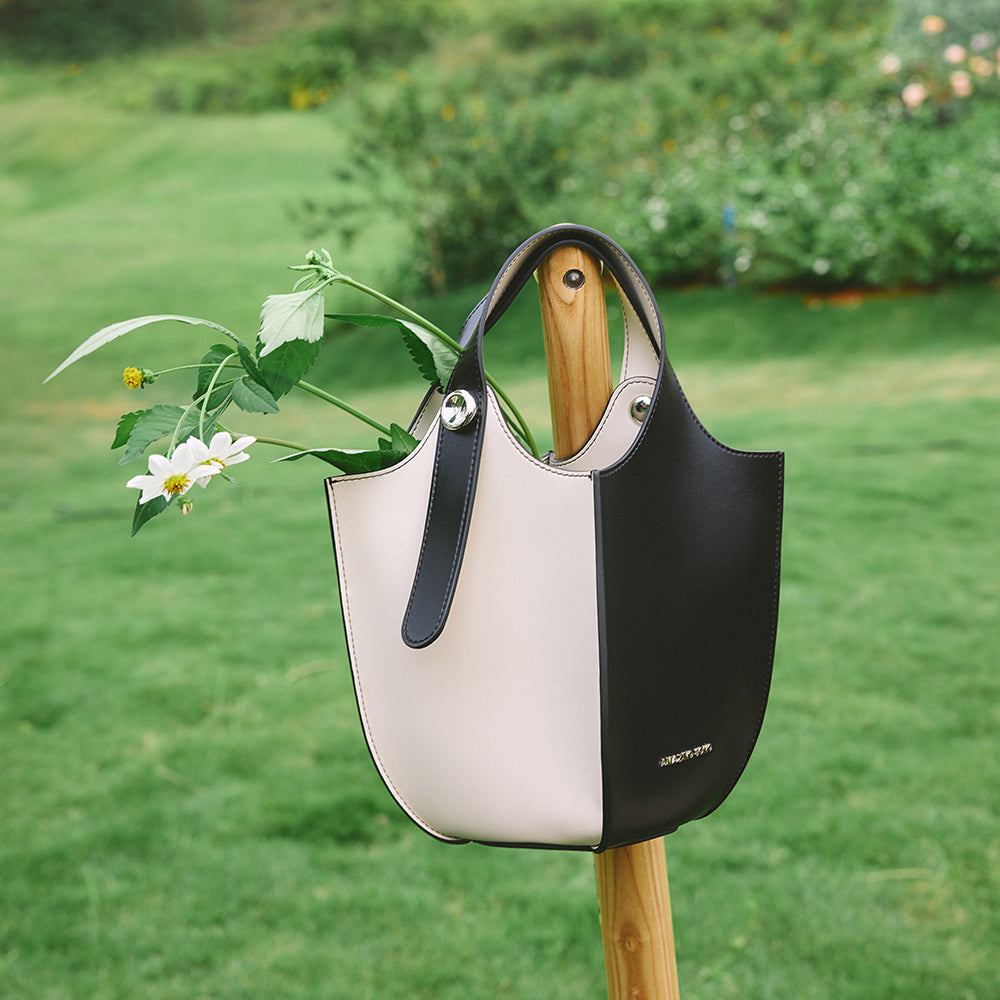 Black and white leather tote bag with flowers, outdoor grass background, Amazing Song