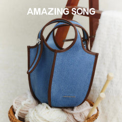 Amazing Song blue denim handbag with brown trim, basket of yarn, cozy home setting