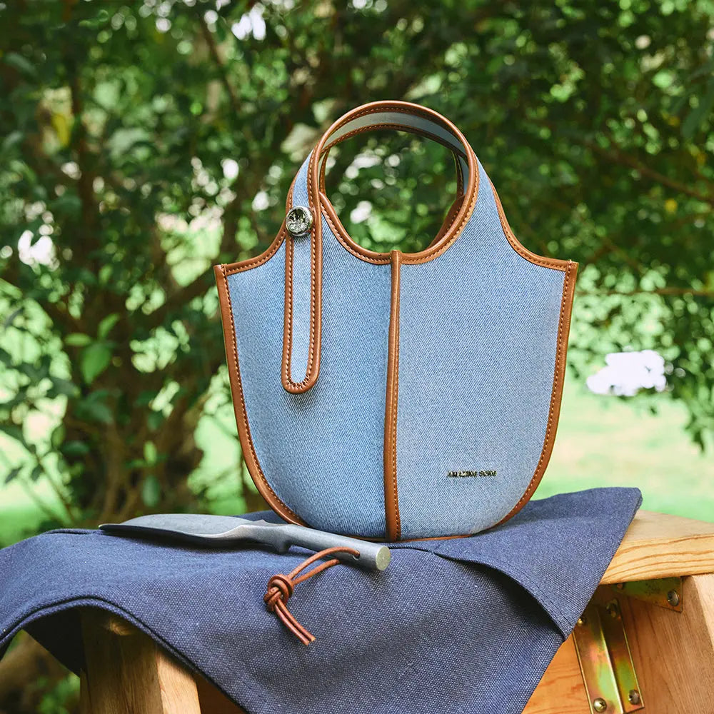 Light blue Amazing Song handbag with brown trim on bench outdoors, official website image