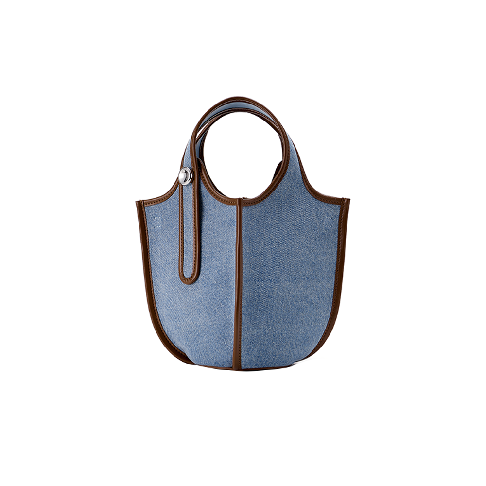 Blue denim tote bag with brown leather trim and round handles on white background