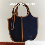Amazing Song navy blue denim handbag with brown leather trim on neutral background