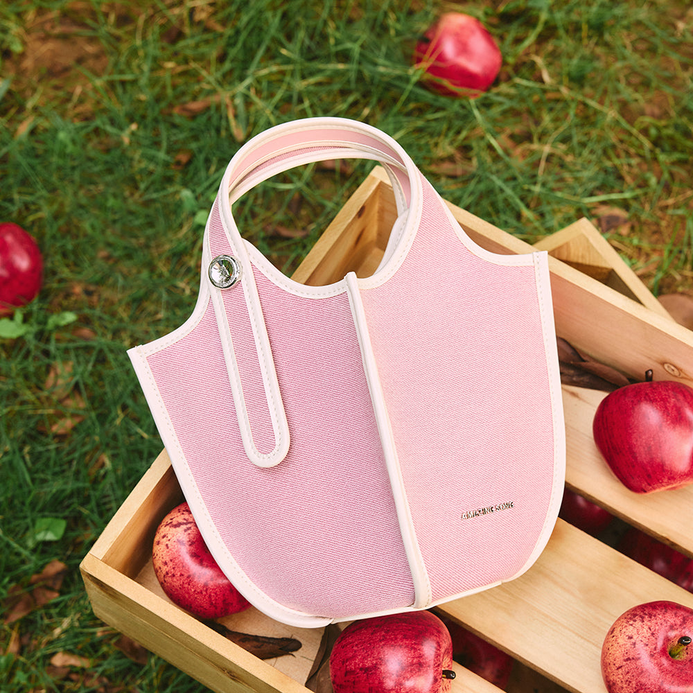 Amazing Song pink handbag on wooden crate with red apples outdoors