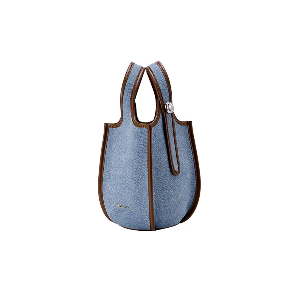Light blue denim tote bag with brown leather trim, displayed on white background