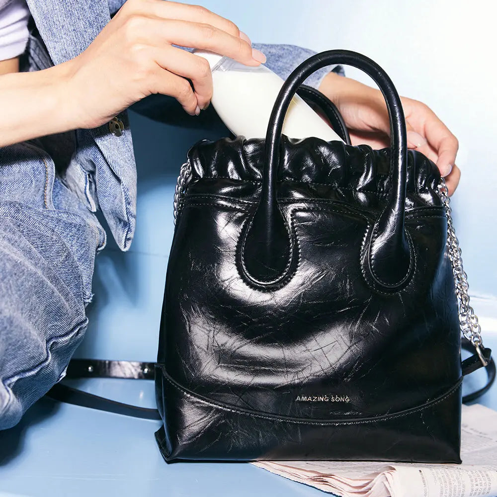 Amazing Song black leather handbag with chain strap, denim outfit, close-up