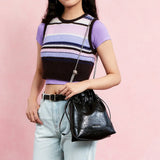 Woman holding Amazing Song black leather handbag with chain strap, stylish casual outfit