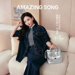 Woman in denim outfit seated on sofa with silver handbag, Amazing Song brand promotion