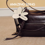 Amazing Song leather bag with flower-shaped tag on beige carpet