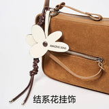 Brown suede handbag with flower-shaped Amazing Song tag and zipper detail