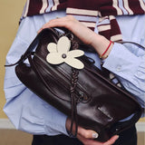 Person holding Amazing Song dark brown leather handbag with butterfly charm