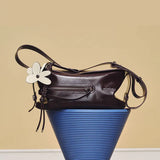 Amazing Song dark brown leather shoulder bag with white flower charm on blue pedestal