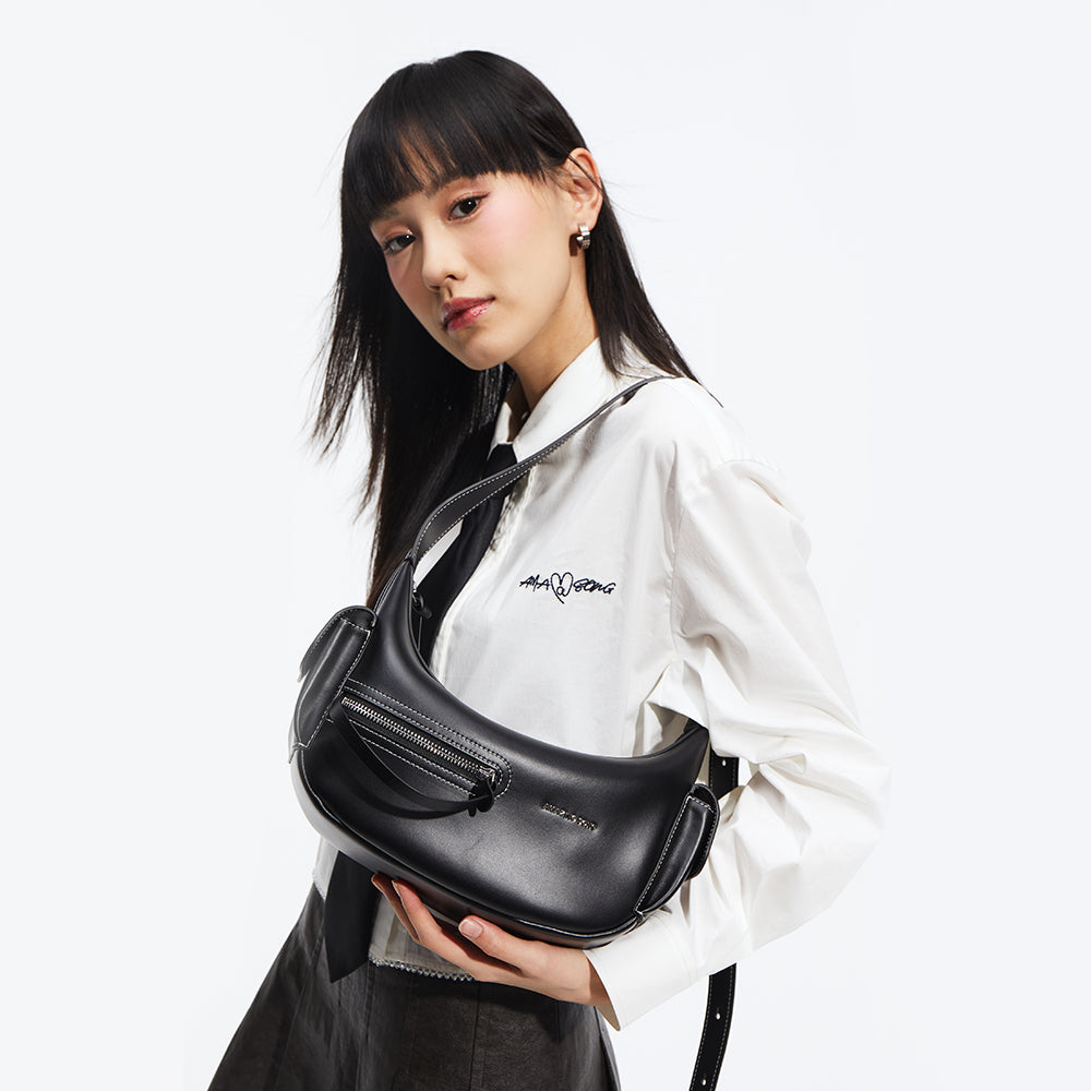 Woman in white shirt holding black Amazing Song shoulder bag against white background