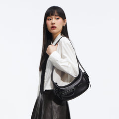 Woman in white shirt and black tie carrying black Amazing Song shoulder bag