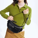 Woman in green sweater holding black Amazing Song shoulder bag against white background