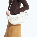 Woman wearing brown top and tan skirt with Amazing Song white shoulder bag