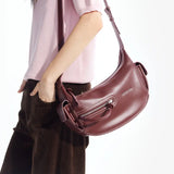 Woman wearing a pink top and brown pants, carrying a maroon Amazing Song shoulder bag