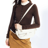 Woman wearing brown top and tan skirt with white Amazing Song shoulder bag