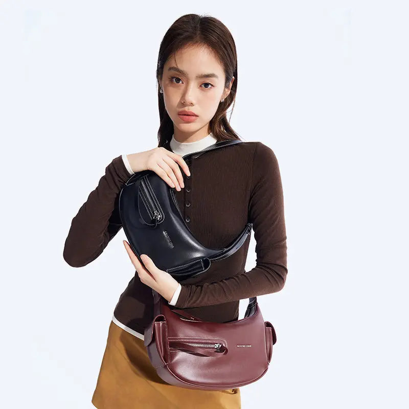 Woman holding black and burgundy Amazing Song handbags against a light background