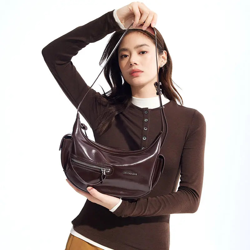 Woman holding a dark brown Amazing Song handbag against a white background