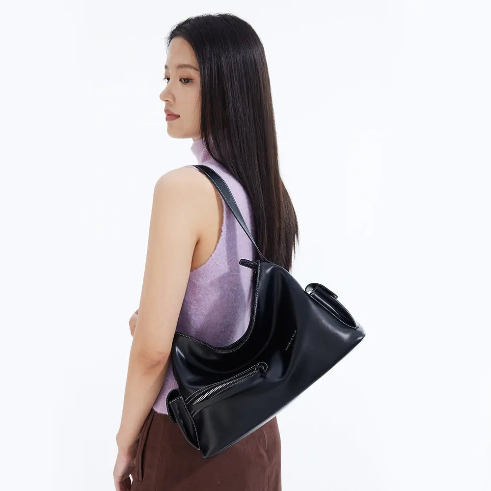 Woman in sleeveless lavender top carrying a sleek black Amazing Song shoulder bag