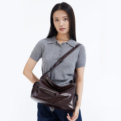 Woman with straight hair wearing a grey collared shirt and carrying a large brown leather shoulder bag