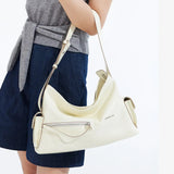 Woman wearing a grey top and blue shorts holding a cream Amazing Song shoulder bag