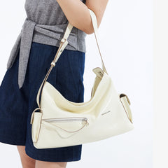 Woman wearing a grey top and blue shorts holding a cream Amazing Song shoulder bag